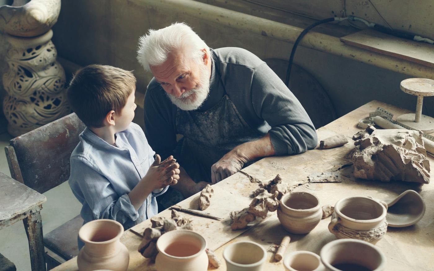 A grandfather teaches a boy pottery. by Vitaly Gariev courtesy of Unsplash.