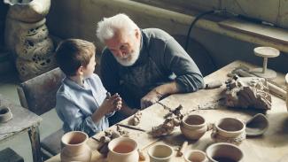 A grandfather teaches a boy pottery. by Vitaly Gariev courtesy of Unsplash.