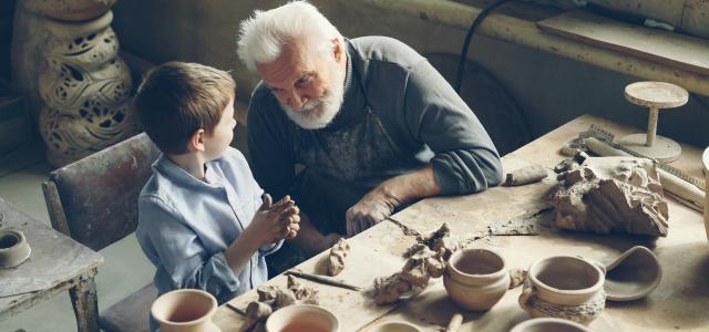 A grandfather teaches a boy pottery. by Vitaly Gariev courtesy of Unsplash.